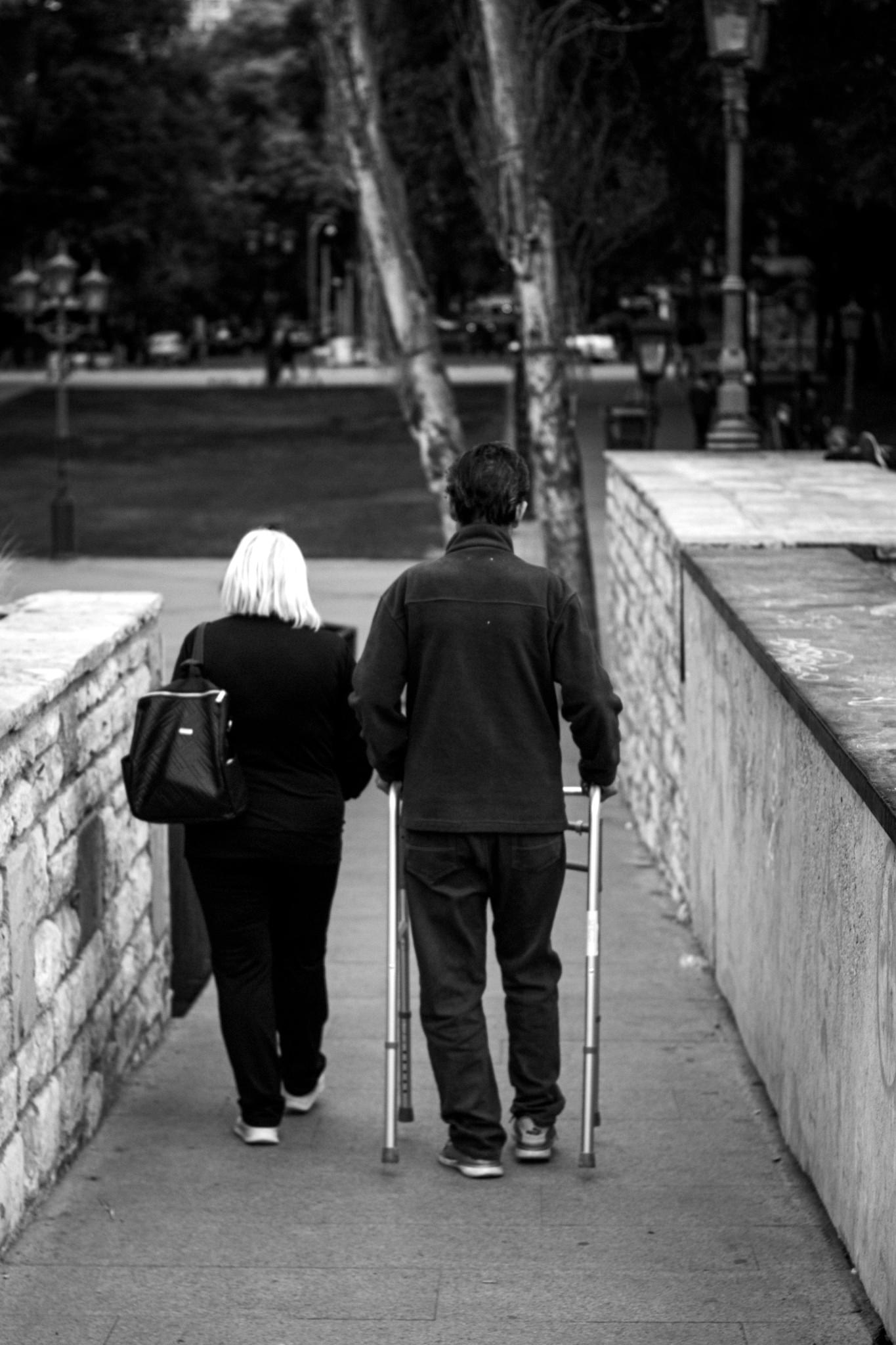 Casal caminhando em uma rampa, com uma pessoa usando apoio de mobilidade